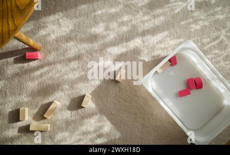 Quelques briques de jouet en bois sur un tapis dans un salon. Le gamin a oublié de nettoyer après avoir joué. Banque D'Images