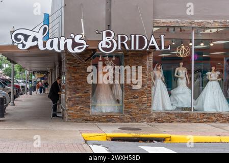 Extérieur de Flan's Bridal shop avec mannequins portant des robes de mariée blanches dans le centre-ville de McAllen, comté de Hidalgo, Texas, États-Unis. Une femme lave les fenêtres. Banque D'Images