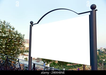 Un panneau d'affichage vide se tient près des rampes et des arbres Banque D'Images