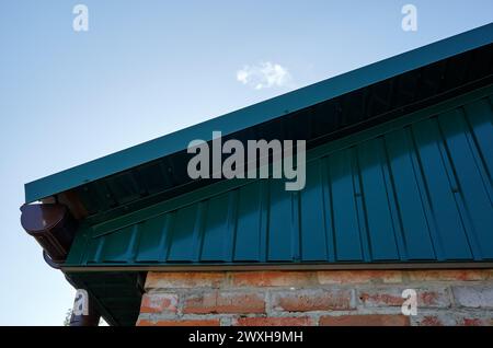 Fragment de toiture métallique de bâtiment rural. Système de drainage de gouttière de support sur le toit Banque D'Images