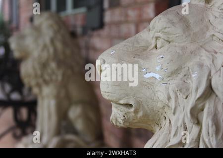 Deux statues de lion montent la garde à l'extérieur d'un ancien bâtiment en briques avec des fenêtres Banque D'Images