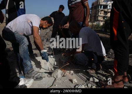 Gaza. 31 mars 2024. Les gens vérifient les décombres après les frappes aériennes israéliennes dans le camp de réfugiés palestiniens de Maghazi dans le centre de la bande de Gaza, le 31 mars 2024. Au moins 36 Palestiniens ont été tués et des dizaines d’autres blessés dans des frappes israéliennes de nuit dans la bande de Gaza, ont annoncé dimanche des sources palestiniennes. Crédit : Xinhua/Alamy Live News Banque D'Images