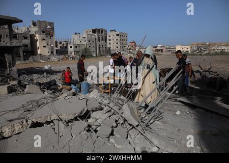 Gaza. 31 mars 2024. Les gens vérifient les décombres après les frappes aériennes israéliennes dans le camp de réfugiés palestiniens de Maghazi dans le centre de la bande de Gaza, le 31 mars 2024. Au moins 36 Palestiniens ont été tués et des dizaines d’autres blessés dans des frappes israéliennes de nuit dans la bande de Gaza, ont annoncé dimanche des sources palestiniennes. Crédit : Xinhua/Alamy Live News Banque D'Images