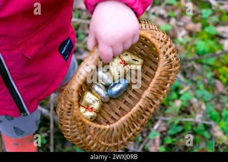 Chasse aux oeufs de Pâques enfant avec panier de chocolat oeufs de Pâques dans Carmarthenshire pays de Galles mars jardin 2024 Royaume-Uni Grande-Bretagne KATHY DEWITT Banque D'Images