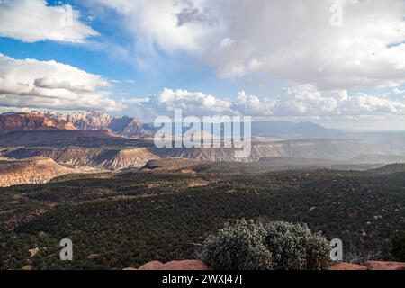 Une vue panoramique sur les montagnes lointaines du parc national de Zion et la vallée environnante avec des nuages bas et de la pluie contre un ciel bleu. Banque D'Images