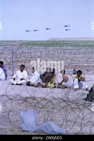 Première Guerre du Golfe : 26 mars 1991 Un essaim d'hélicoptères Apache de l'armée américaine survolent des prisonniers de guerre irakiens dans un complexe temporaire de l'armée américaine dans le sud de l'Irak. Banque D'Images