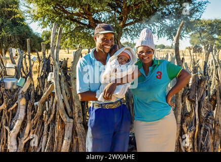 père africain et mère avec un bébé dans le village en face de la cuisine extérieure, ong aide à la charité Banque D'Images