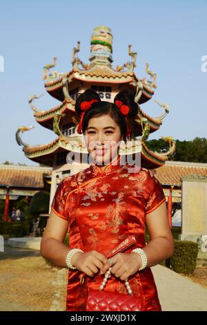 Portrait d'une belle femme asiatique dans une robe chinoise rouge pose et debout devant la pagode chinoise à l'intérieur d'un sanctuaire. Banque D'Images