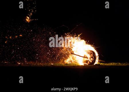 31 mars 2024, Rhénanie du Nord-Westphalie, Lügde : une roue de Pâques historique descend une colline en feu. Depuis 2018, la course de roues de Pâques de Lügde fait partie du patrimoine culturel immatériel allemand de l'UNESCO. Pendant le spectacle, d’énormes roues en bois bourrées de paille descendent une colline l’une après l’autre peu avant 21 heures. Photo : Christoph Reichwein/dpa Banque D'Images