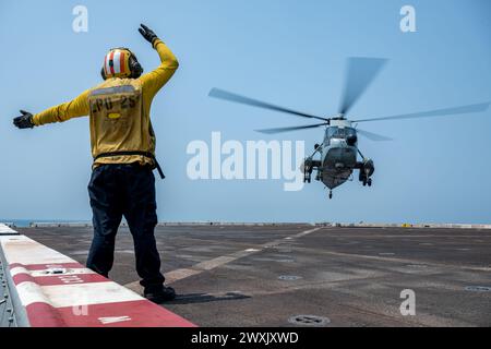 Avion Boatswain’s Mate (Handling) 3rd Class Michael Aguilar, originaire de Glendale, Californie, envoie des signaux à un Sea King UH-3H de la marine de la République de l’Inde sur le pont d’envol du quai de transport amphibie USS Somerset de classe San Antonio (LPD 25) alors qu’il était en route dans la baie du Bengale, Mar. 28, 2024, pendant l'exercice Tiger TRIUMPH 2024. Tiger TRIUMPH est un exercice amphibie de trois services entre les États-Unis et l'Inde axé sur l'aide humanitaire et la préparation et l'interopérabilité des secours en cas de catastrophe. (Photo de l'US Navy par Evan Diaz, spécialiste des communications de masse, 2e classe) Banque D'Images