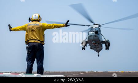 Aviation Boatswain's Mate (Handling) 3rd Class Qwashewn Mayes, originaire de Memphis, Tennessee, envoie des signaux à un Sea King de la marine de la République de l'Inde sur le pont d'envol du navire de transport amphibie USS Somerset de classe San Antonio (LPD 25) alors qu'il était en route dans la baie du Bengale, Mar. 28, 2024, pendant l'exercice Tiger TRIUMPH 2024. Tiger TRIUMPH est un exercice amphibie de trois services entre les États-Unis et l'Inde axé sur l'aide humanitaire et la préparation et l'interopérabilité des secours en cas de catastrophe. (Photo de l'US Navy par Evan Diaz, spécialiste des communications de masse, 2e classe) Banque D'Images