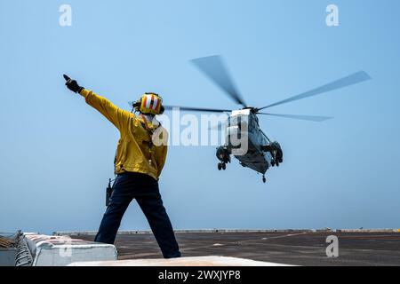 Avion Boatswain’s Mate (Handling) 1st Class Reyvin Olaes, originaire de Cavite, Philippines, envoie des signaux à un Sea King de la marine de la République de l’Inde, UH-3H, sur le pont d’envol du navire de transport amphibie USS Somerset de classe San Antonio (LPD 25) alors qu’il se dirigeait dans la baie du Bengale, Mar. 28, 2024, pendant l'exercice Tiger TRIUMPH 2024. Tiger TRIUMPH est un exercice amphibie de trois services entre les États-Unis et l'Inde axé sur l'aide humanitaire et la préparation et l'interopérabilité des secours en cas de catastrophe. (Photo de l'US Navy par Evan Diaz, spécialiste des communications de masse, 2e classe) Banque D'Images