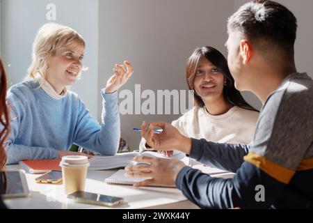 Un groupe d'étudiants ciblés s'engagent activement dans des discussions académiques, illustrant la dynamique de l'apprentissage collaboratif dans un cadre de classe lumineux Banque D'Images