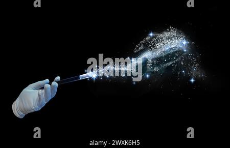 Magicien avec baguette magique exécutant un tour sur fond noir, gros plan Banque D'Images