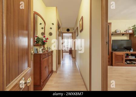 Hall d'entrée de la maison avec porte en bois de chêne blindé, planchers en bois assortis, buffet avec miroir assorti et murs jaune pâle Banque D'Images