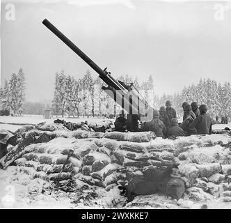 Légende originale : équipage de canon de la «Black Widow», canon anti-aérien de 90 mm creusé à l'extérieur de Bastogne, Belgique, sur le point de tirer sur un avion ennemi aperçu dans la région. Batterie B 217ème Bn (radar) Bastogne. env. 1945 Banque D'Images