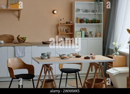 Image de fond de l'intérieur de cuisine confortable avec des comptoirs blancs modernes et un ensemble de table en bois pour l'espace de copie du petit déjeuner Banque D'Images