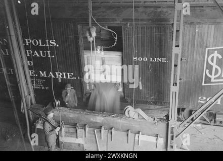 Pillsbury Flour Mills, Minneapolis, MN - déchargement de blé à l'aide de pelles actionnées par moteur, ouvrier et soldat dans l'image CA. 1917 Banque D'Images