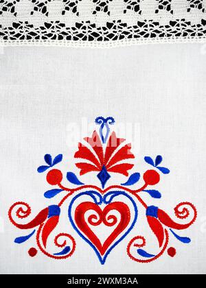 Ornement traditionnel slovène de broderie de nappe dans des couleurs bleues et rouges avec fleur d'oeillet et un coeur Banque D'Images