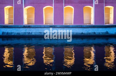 Passerelle piétonne illuminée le long de la rivière Memminger Ach à Memmingen et le reflet de l'architecture dans l'eau Banque D'Images