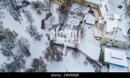 Photographie par drone d'un petit parc public avec une haie couverte de neige dans une ville pendant la journée nuageuse d'hiver Banque D'Images