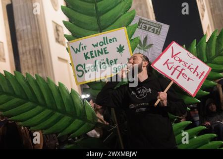 Berlin, Allemagne. 31 mars 2024. Un homme fume un joint lors d'une entrée de fumée devant la porte de Brandebourg. À partir du 1er avril, les adultes âgés de 18 ans et plus seront autorisés à posséder 25 grammes dans les lieux publics. Crédit : Sebastian Gollnow/dpa/Alamy Live News Banque D'Images