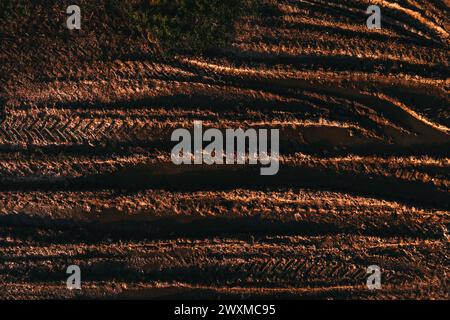 Marques de bande de roulement, vue de dessus de la sculpture des pneus du tracteur dans un sol boueux ou une route de terre de campagne, prise de vue aérienne par drone pov Banque D'Images