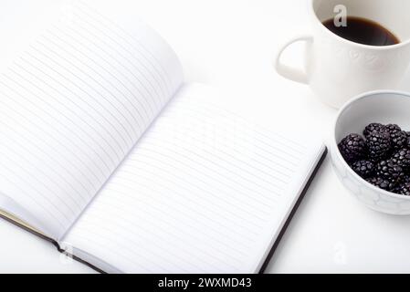 Journal ouvert sur le bureau blanc avec café et baies Banque D'Images