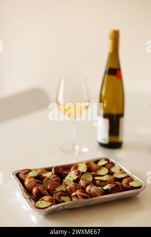 escargots prêts à cuire avec du beurre et des herbes et du vin sur la table Banque D'Images