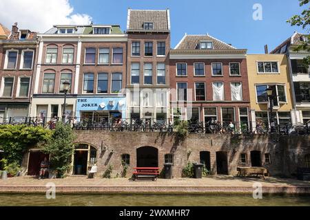 Bâtiments colorés au bord du canal avec un bar et des sièges en plein air au-dessus d'un remblai de briques le long de l'eau lors d'une journée ensoleillée à Utrecht, Hollande, pays-Bas Banque D'Images