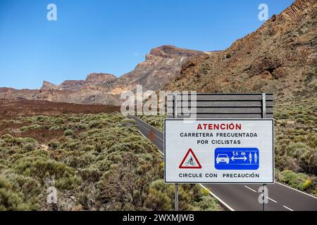 Panneau d'avertissement cycliste en espagnol avec le paysage de montagne de Tenerife en arrière-plan sous un ciel bleu clair Banque D'Images