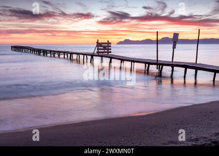 Beau lever de soleil sur une plage avec une vieille jetée en bois à Platja de Muro, Majorque, Îles Baléares, Espagne Banque D'Images