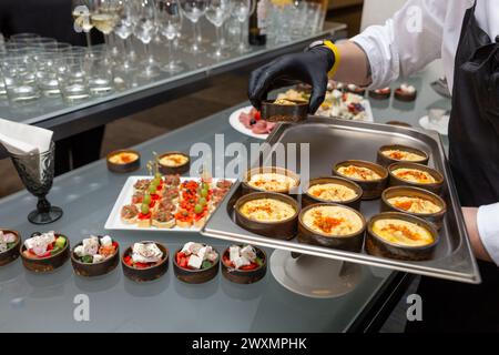 Le serveur place des collations sur la table de fête. Buffet, repas de restauration au restaurant, mini canapés, collations et hors-d'œuvre Banque D'Images