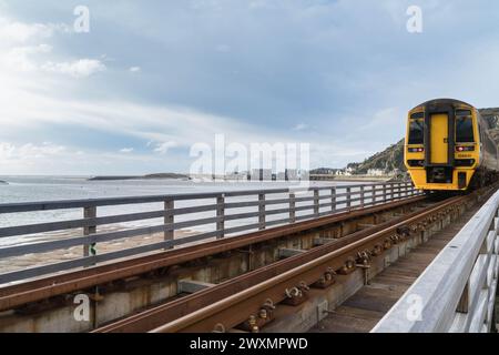 Le train de 15h40 de Fairbourne fait un chemin à travers le Pont Abermaw vers la gare de Barmouth Gwynedd Wales UK. Mars 2024 Banque D'Images