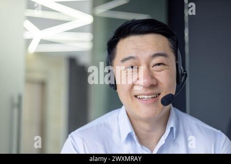Un homme asiatique est photographié travaillant intensément dans un bureau contemporain bien éclairé, dégageant une atmosphère professionnelle. Banque D'Images
