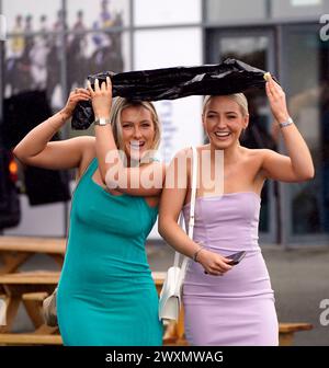 Les amateurs de courses s'abritent de la pluie lors du Fairyhouse Easter Festival 2024 à Fairyhouse Racecourse dans le comté de Meath, Irlande. Date de la photo : lundi 1er avril 2024. Banque D'Images