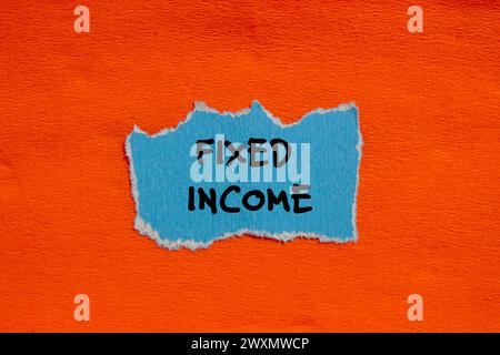 Mots à revenu fixe écrits sur un morceau de papier bleu déchiré avec un fond orange. Symbole commercial conceptuel. Copier l'espace. Banque D'Images