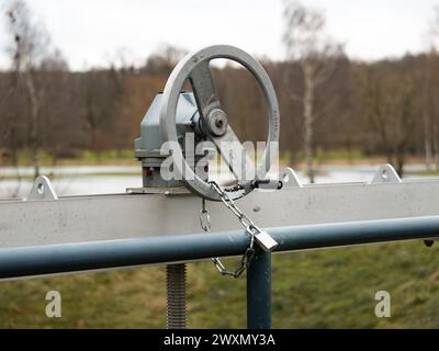 Manivelle manuelle pour ouvrir et fermer une trappe. La rotation est bloquée par une chaîne avec un verrou. Ajustement de l'entrée d'eau d'un petit courant. Banque D'Images