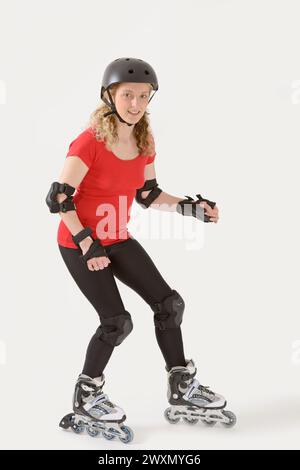 Jeune femme sur rollers, vêtu d'un ensemble complet des protecteurs et un casque Banque D'Images