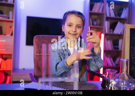 Science, passe-temps, apprentissage, éducation, découverte, enfance et vie domestique. Petite fille caucasienne concentrée faisant des expériences de chimie en regardant tes Banque D'Images