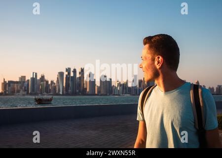 Portrait d'un homme regardant en arrière l'horizon urbain de Doha. Voyageur seul au Qatar. Banque D'Images