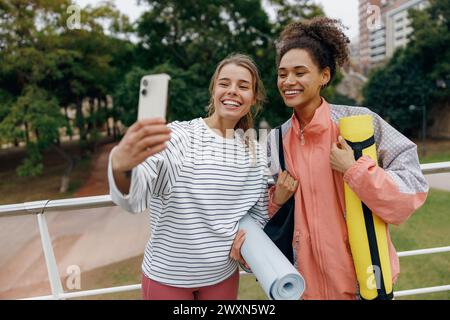 Deux femmes de fitness souriantes faisant selfie au téléphone après l'entraînement en plein air du matin Banque D'Images