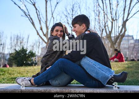 jeune couple assis et serrant sur un banc de parc. concept d'amour et de relations Banque D'Images