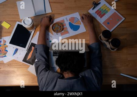 L'homme qui travaillait tard s'est endormi avec son ordinateur portable toujours au travail Banque D'Images