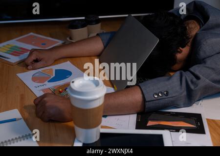 L'homme qui travaillait tard s'est endormi avec son ordinateur portable toujours au travail Banque D'Images