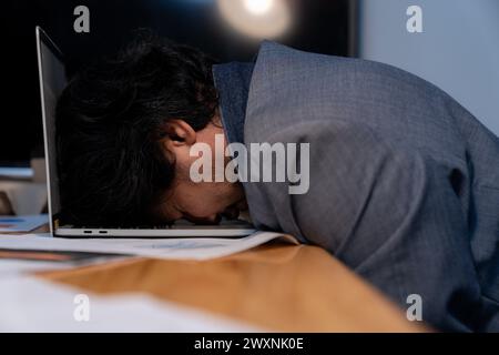 L'homme qui travaillait tard s'est endormi avec son ordinateur portable toujours au travail Banque D'Images