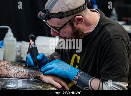 Homme se faisant tatouer un bras à Scottish Tattoo Convention, Édimbourg, Écosse, Royaume-Uni Banque D'Images