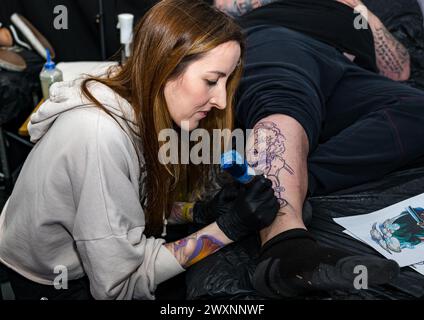 Homme se faisant tatouer une jambe à Scottish Tattoo Convention, Édimbourg, Écosse, Royaume-Uni Banque D'Images