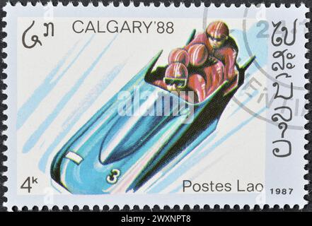 Timbre-poste oblitéré imprimé par le Laos, qui fait la promotion des Jeux olympiques d'hiver à Calgary, vers 1987. Banque D'Images