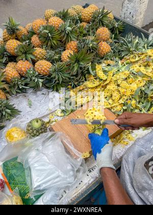 Couper et vendre des tranches d'ananas frais sur un étal de fruits de rue à Chittagong, au Bangladesh Banque D'Images